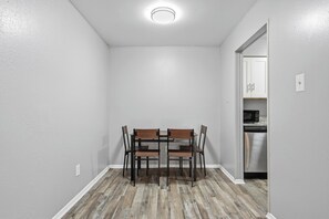 A dining area with a table and chairs, a kitchen with appliances, and a door leading to another room. - 2-bedroom with large living area (Denton)
