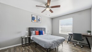 A bedroom with a bed, a desk, a chair, a ceiling fan, and a window. - Denton pad with 2BR comfort (Denton)