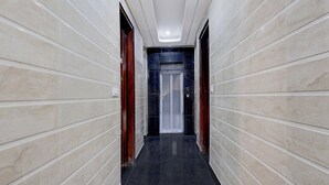 A hallway with marble walls and a black floor, leading to a door with a glass panel. - Townhouse Phase 3 DLF Cyber City (Gurugram)