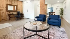 Ein geräumiger Wohnbereich mit einem runden Glastisch, einem blauen Sofa und einem modernen Kamin.