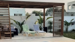 A rectangular swimming pool with a wooden pergola overhead, surrounded by lounge chairs and potted plants. - Luxurious Villa Rental in Houmt Souk, Djerba - Perfect Family Retreat (Houmt Souk)