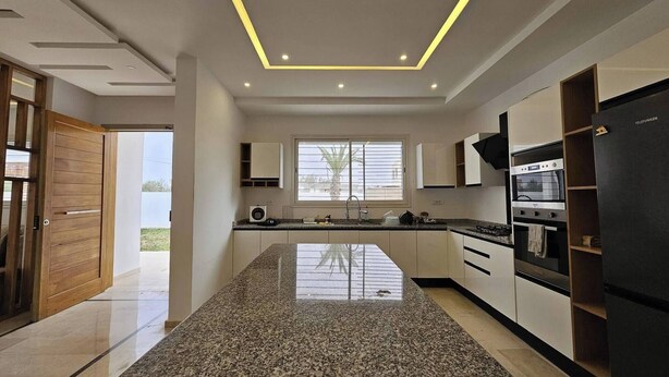 A modern kitchen with a granite countertop, built-in appliances, and a large window providing natural light. - Luxurious Villa Rental in Houmt Souk, Djerba - Perfect Family Retreat (Houmt Souk)