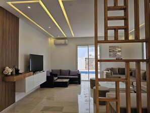 Una sala de estar moderna con un televisor de pantalla plana, un sofá y un separador de madera.