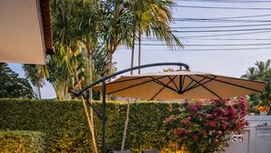 Un espace patio aménagé avec des fauteuils de jardin, une pergola et un éclairage décoratif.