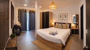 Une chambre moderne avec un grand lit, des tables de chevet, un luminaire suspendu et une vue sur l’extérieur.