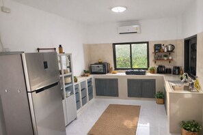 Eine moderne Küche mit integriertem Kühlschrank, Mikrowelle und Herd. Ein Fenster sorgt für natürliches Licht und bietet Blick ins Grüne.