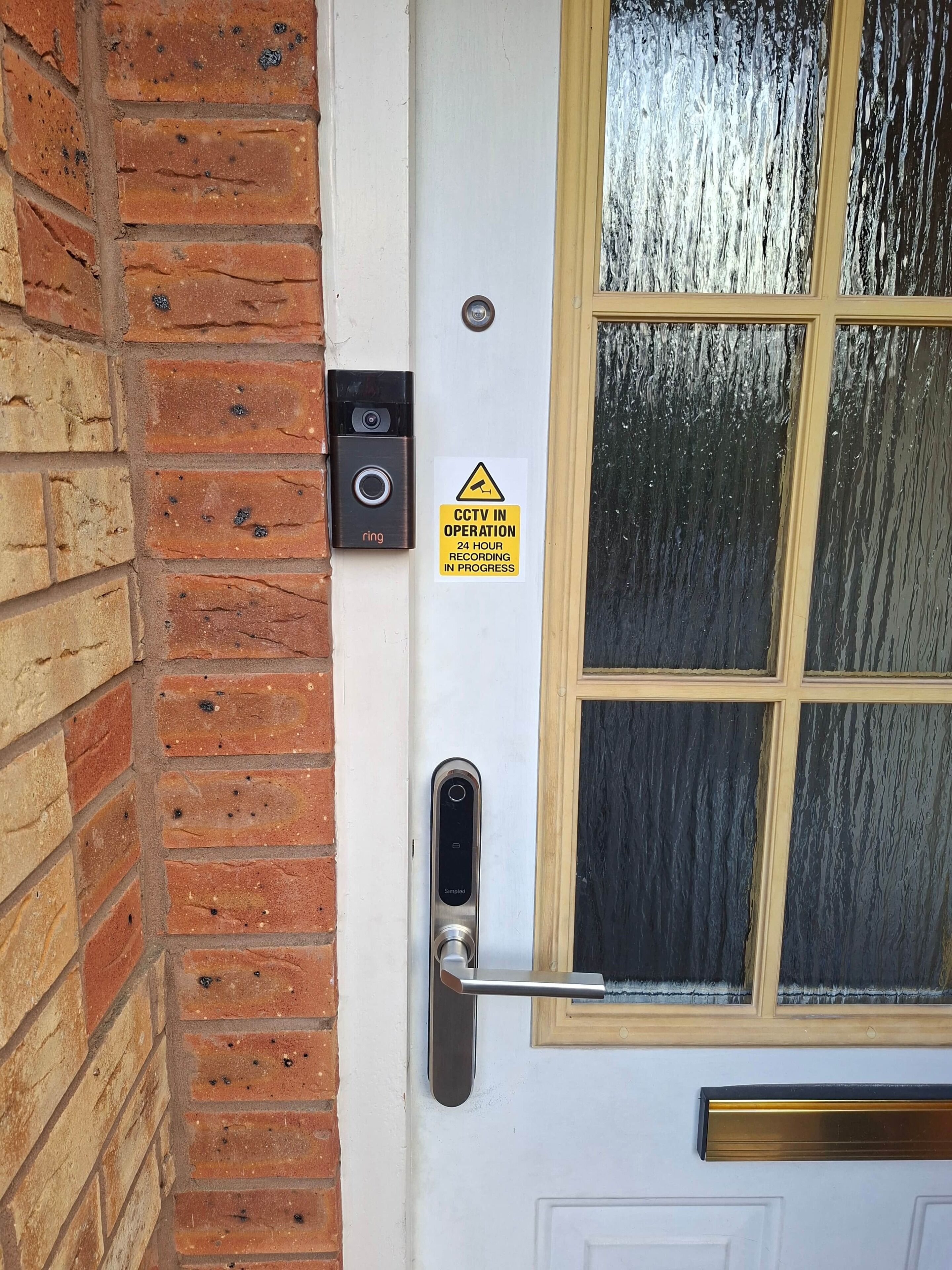 Una porta con un cartello per telecamere di sicurezza, un campanello e una serratura a combinazione.