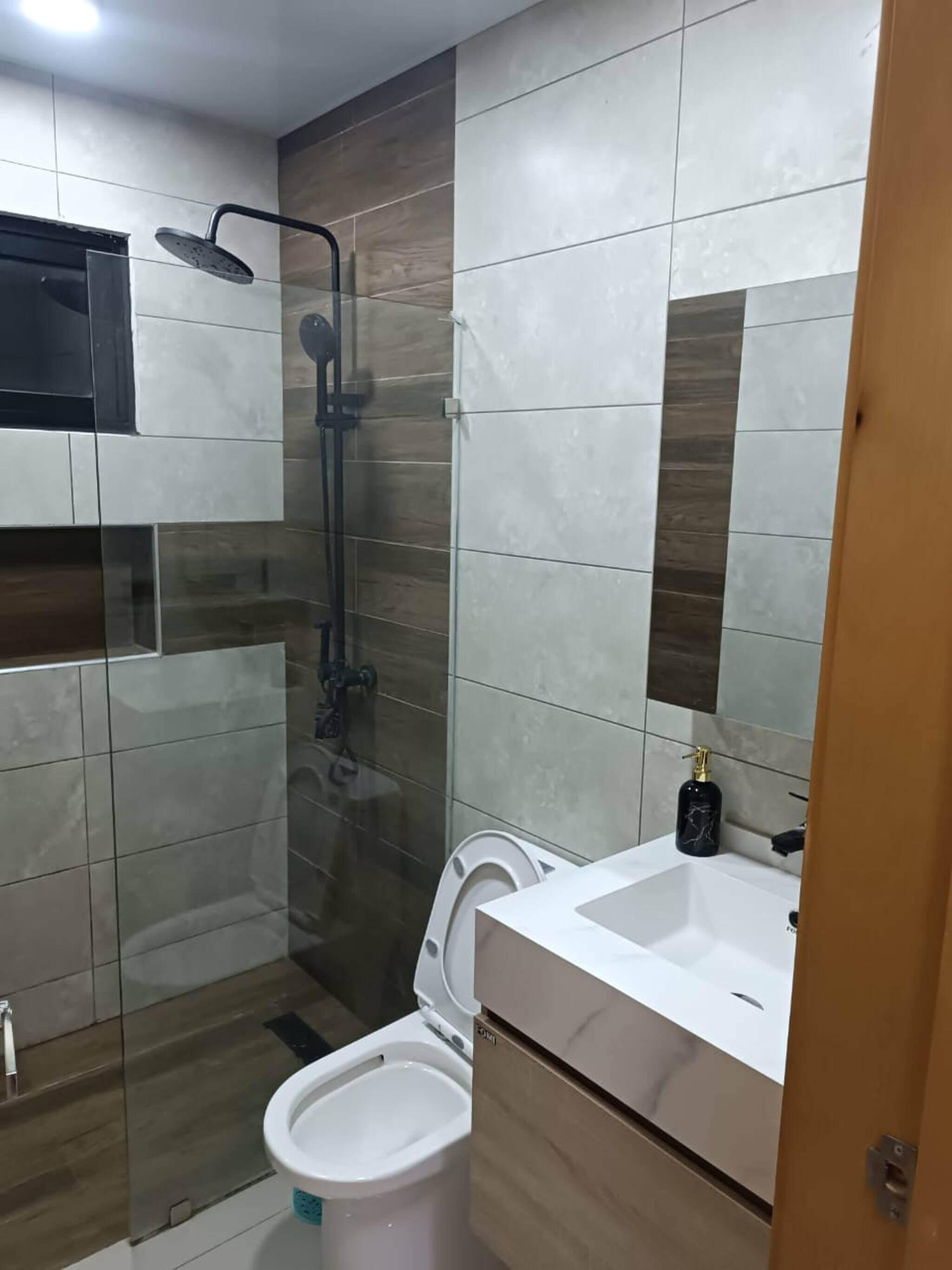 Een moderne badkamer met een douchecabine van glas, een wit toilet en een wastafel met een marmeren aanrechtblad.