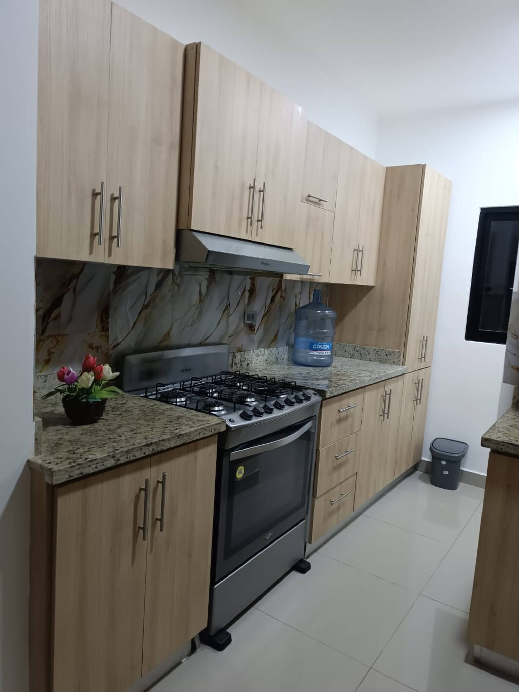A kitchen with wooden cabinets, a gas stove, an oven, and a marble backsplash.