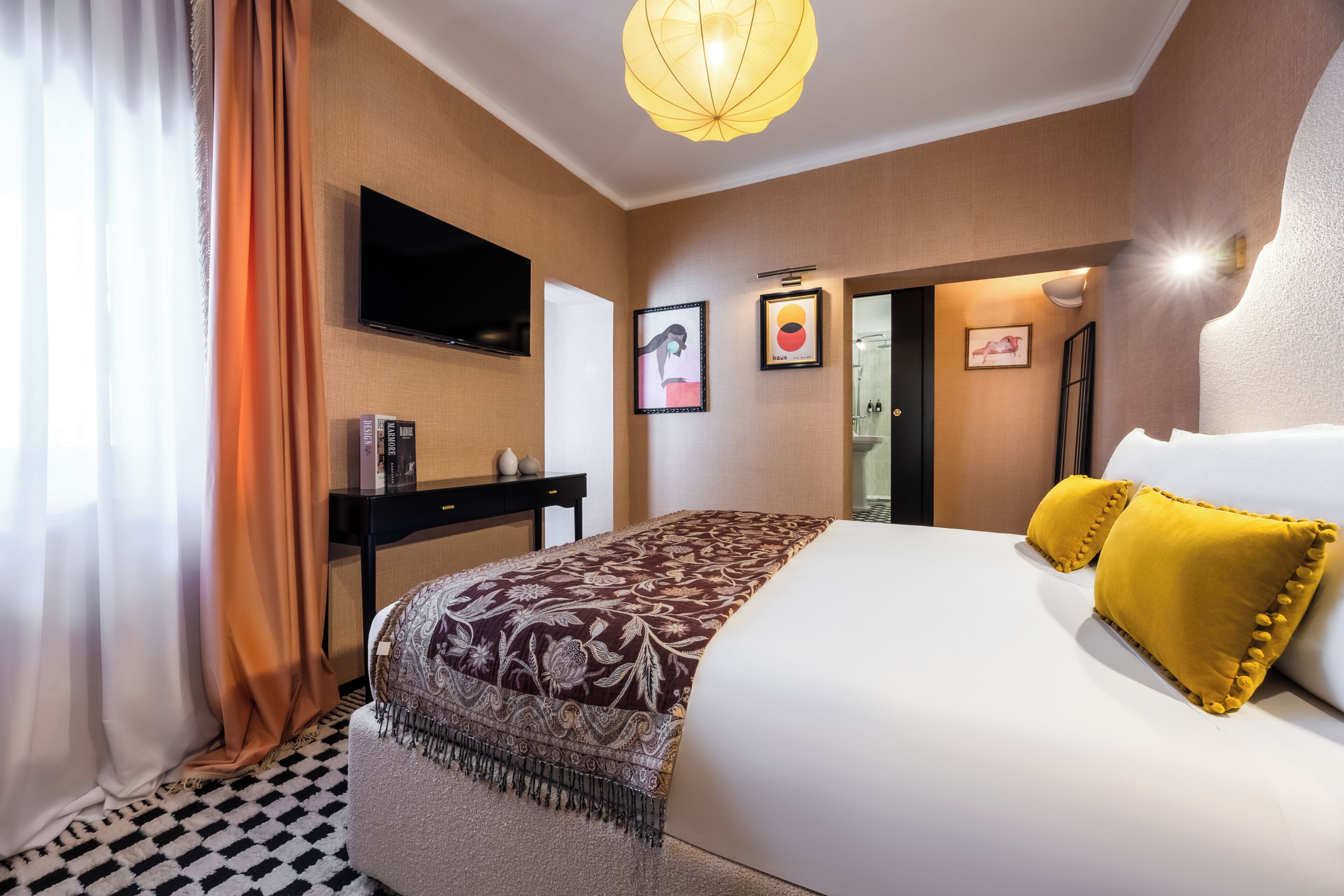 Une chambre d’hôtel équipée d’un lit, d’une télévision, d’un bureau et d’une porte donnant accès à une salle de bain.