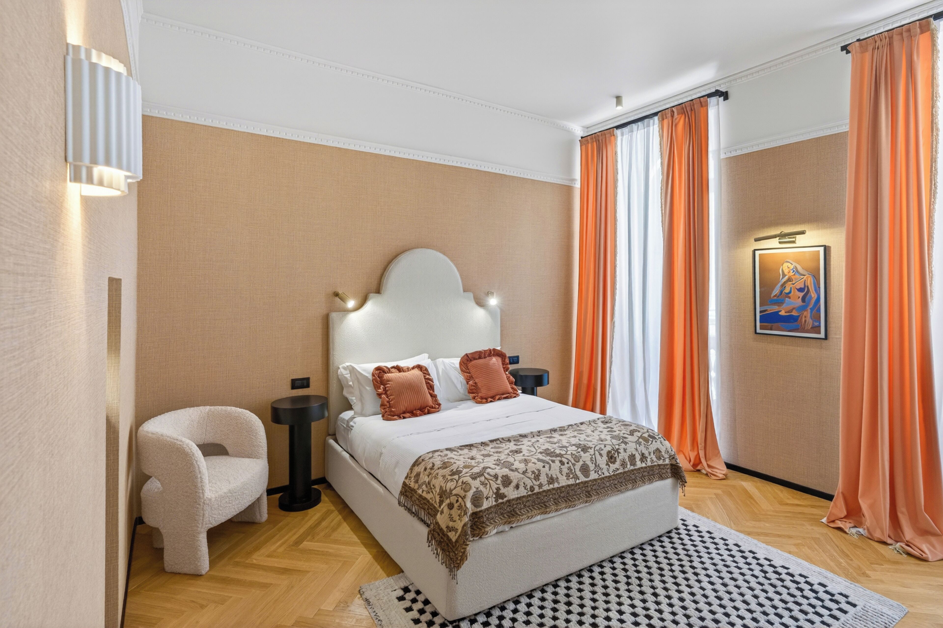 A bedroom with a bed, a chair, a nightstand, a lamp, and a painting on the wall.