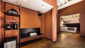 Un intérieur moderne avec un parquet en chevrons, une étagère noire contenant divers objets, un canapé blanc et un plafond avec des poutres apparentes.