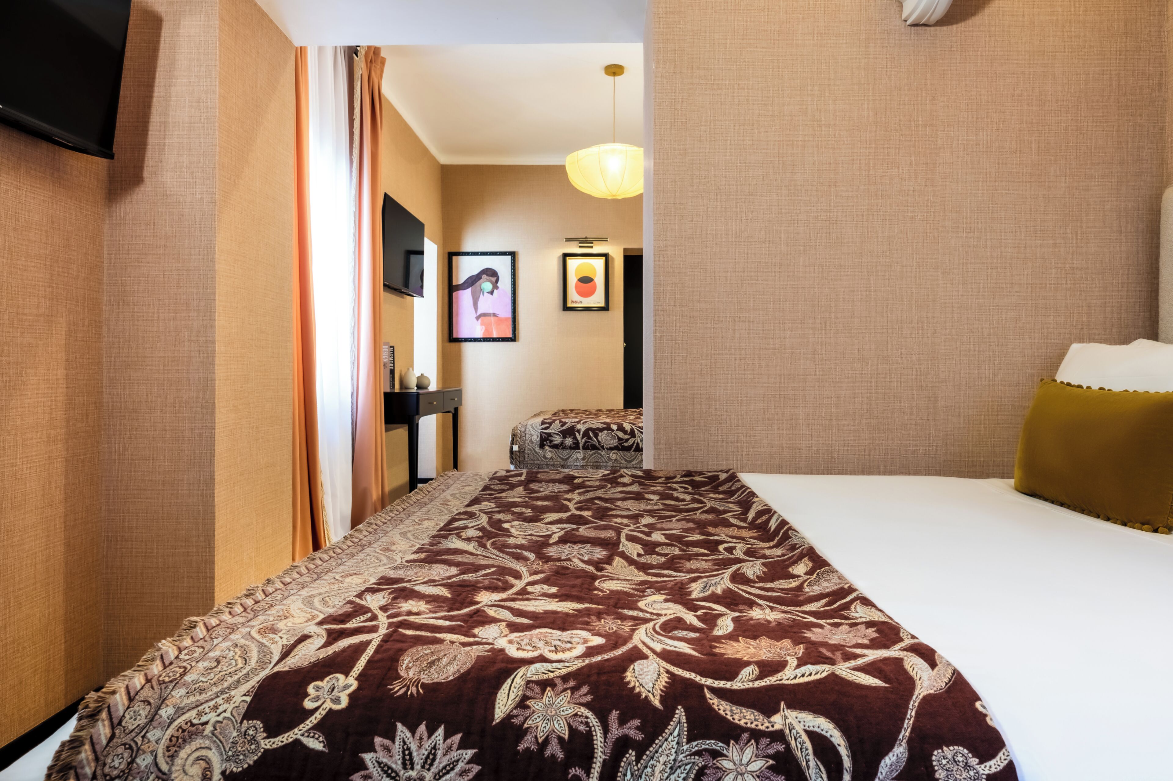 Habitación de hotel con una cama grande, televisión, un cuadro en la pared y alfombra estampada.