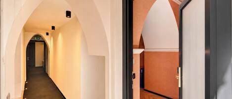 A hallway with an arched ceiling, a door with a number, and a wooden floor.