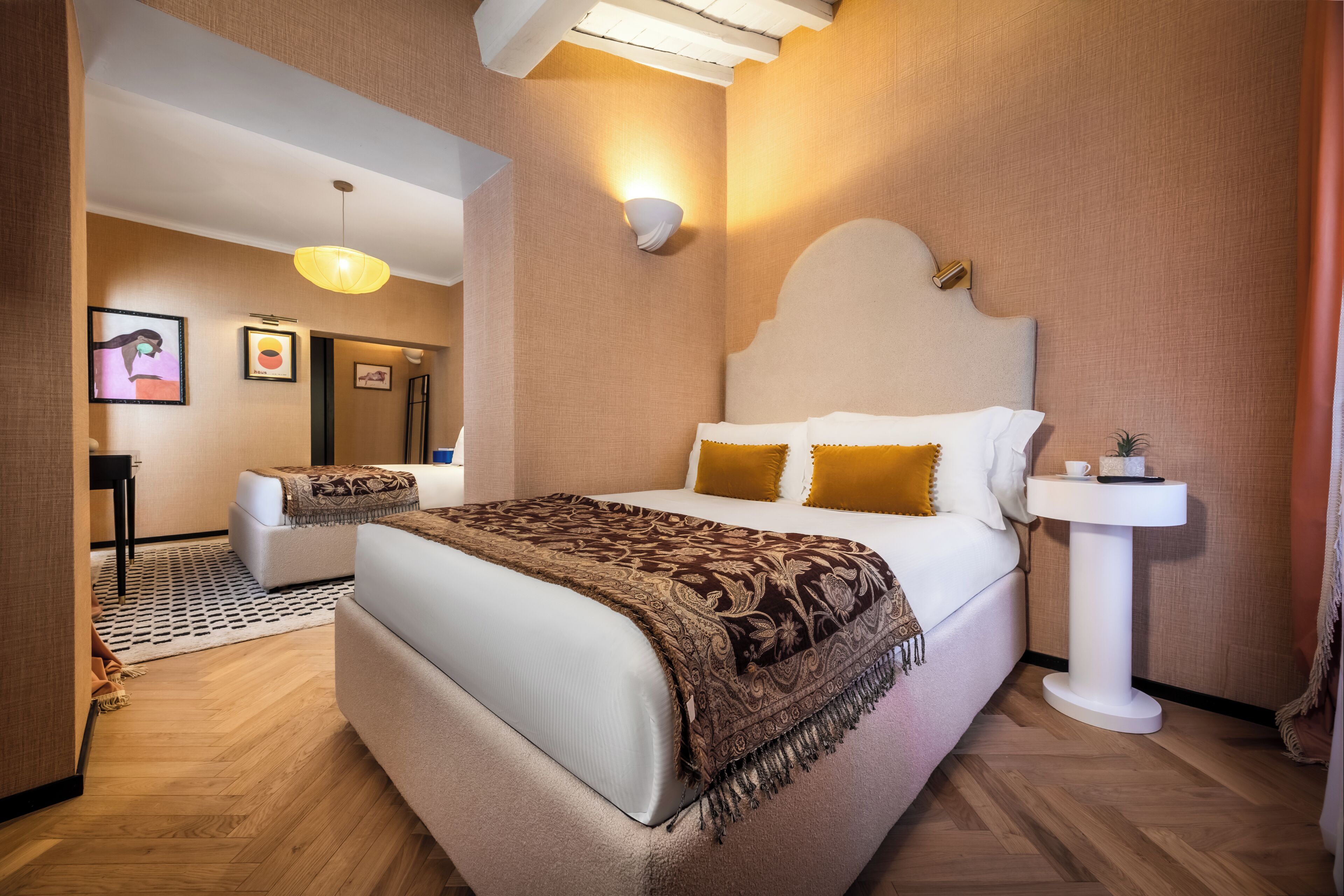 A modern hotel room with a bed, bedside table, and a small white pedestal.