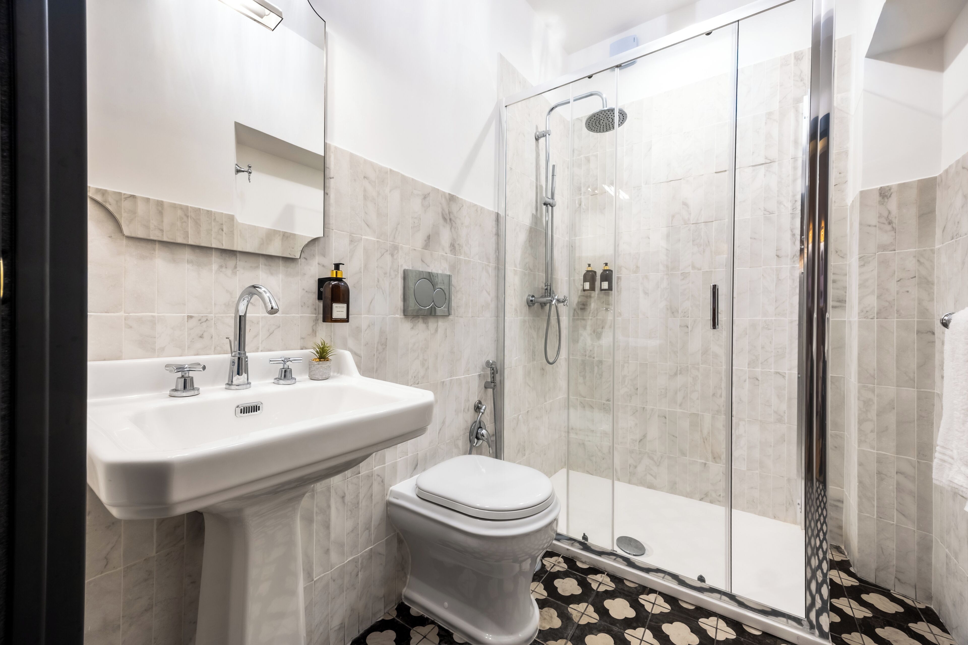 A modern bathroom with a glass-enclosed shower, a white sink, and a toilet.