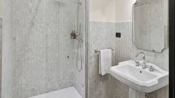 A bathroom with a shower, a sink, and a mirror.
