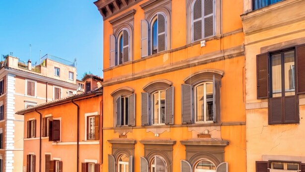 Une rue avec des terrasses, un restaurant et un immeuble avec une porte verte.