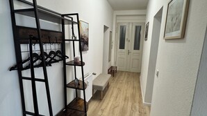 A hallway with a black metal rack, a bench, and a door at the end. - Arminos Apartment (Chemnitz)