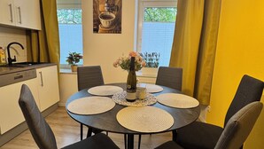 A dining area with a round table, black chairs, and a bottle of wine. There are three pendant lights above the table. - Arminos Apartment (Chemnitz)