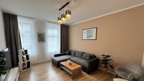 A modern living room with a grey sofa, a wooden coffee table, and a TV on a stand. - Arminos Apartment (Chemnitz)