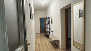 A hallway with a wooden floor, a bench, a radiator, and a shelf with items. - Arminos Apartment (Chemnitz)