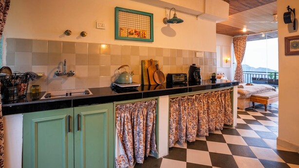 A kitchen with a checkered floor, a stove, a kettle, and a toaster. - Liveaway Dharamkot by PACK (McLeod Ganj)