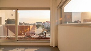 Ein Zimmer mit einer großen Schiebeglastür, die auf einen Balkon mit Sitzmöbeln führt.