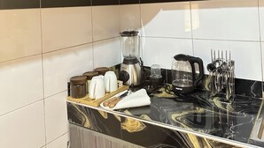 Et køkken med marmor bordplade, kaffemaskine, elkedel og et knivdisplay.