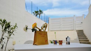 Una mesa con una bolsa de papel marrón, una rosa blanca, una taza pequeña y una máquina de café.