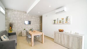 Una sala de estar moderna con una pared de piedra, una mesa de comedor de madera y un armario blanco.