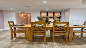 A dining area with a wooden table and chairs, a vase with flowers, and a door with curtains. - Stylish City Centre Hideaway & Hot Tub (Galway)