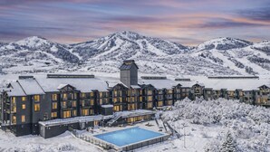 Un hotel con varias edificaciones, piscina y montañas nevadas al fondo.
