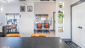 Een moderne kantoorruimte met een lange tafel, twee bureaustoelen, een computerinrichting en een deur met een wasserette.