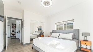 Een moderne slaapkamer met een groot bed, nachtkastjes, een spiegel en een raam.