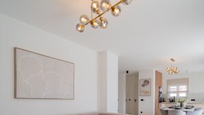 Una sala moderna con un amplio sofá seccional en forma de L, una mesa de centro de madera y un comedor con una mesa redonda y sillas.