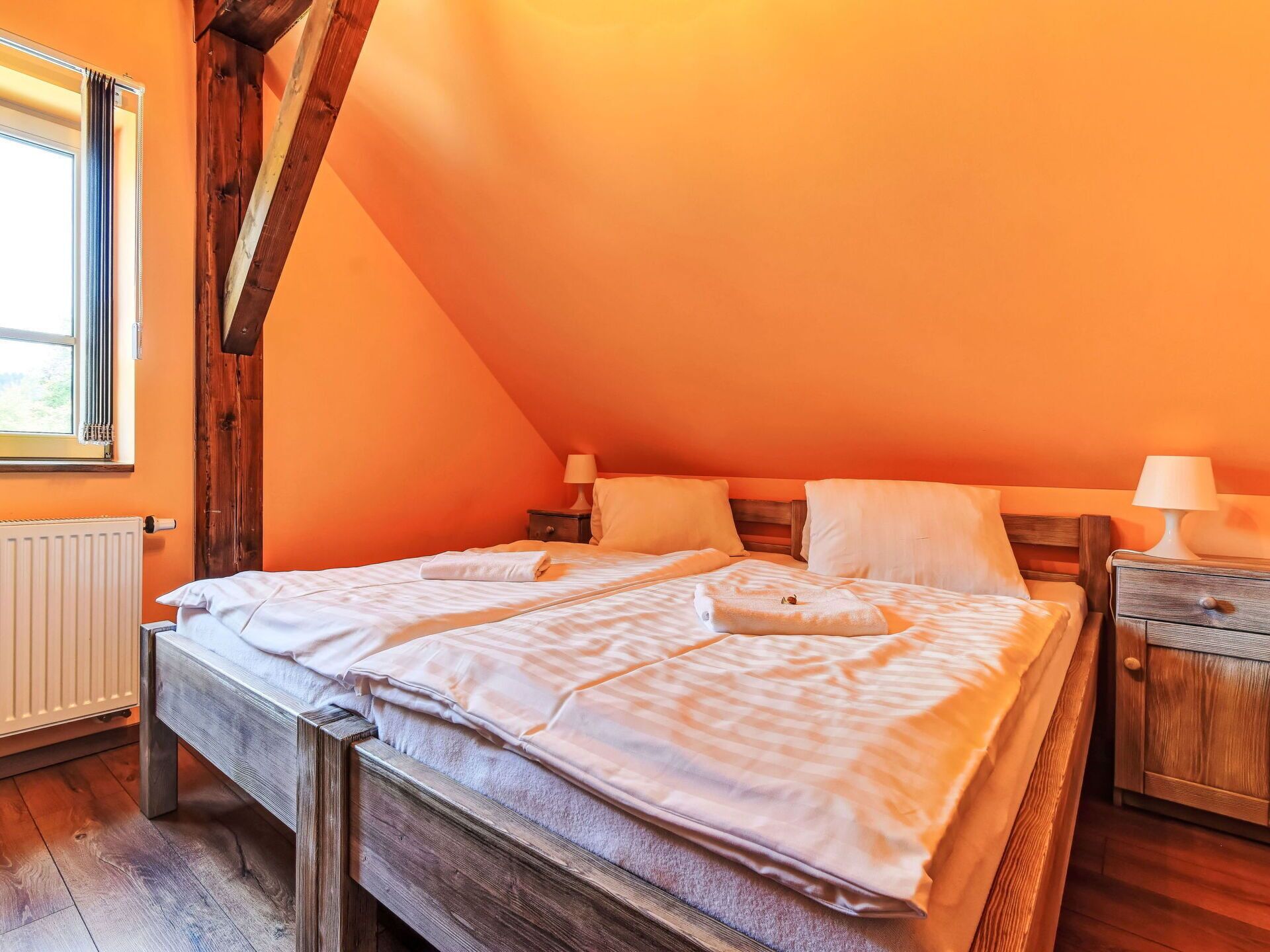 Una camera accogliente con un letto di legno, due comodini e una finestra con tende.