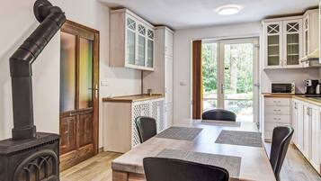 A compact kitchen with a wood-burning stove, white cabinets, and a dining area with a table and chairs.
