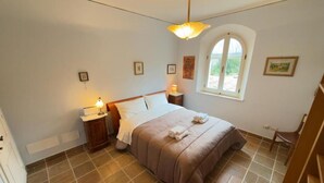 A bedroom with a bed, a nightstand, a lamp, a window, and a door. - Stunning private villa for 10 guests with hot tub, A/C, WIFI, TV and patio (Montepulciano)