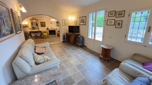 A spacious living room with a fireplace, a television, and a dining area in the background. - Stunning private villa for 10 guests with hot tub, A/C, WIFI, TV and patio (Montepulciano)