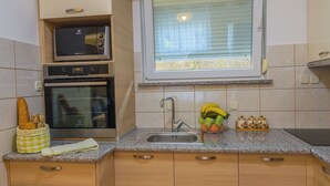 Een koffiezetapparaat/waterkoker, een koelkast, een oven, een kookplaat