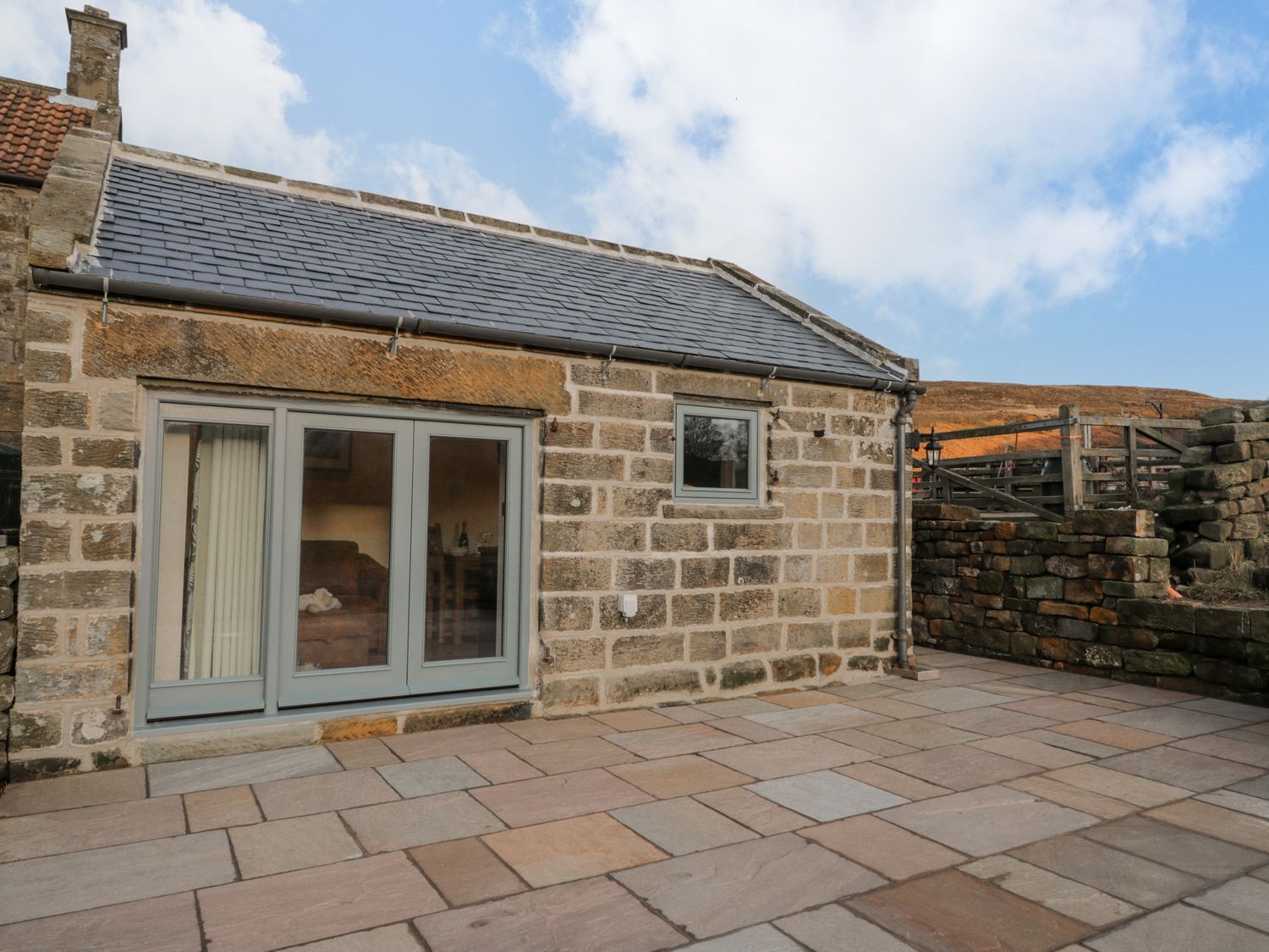 A stone building with a tiled roof, a large sliding glass door, and a small window.