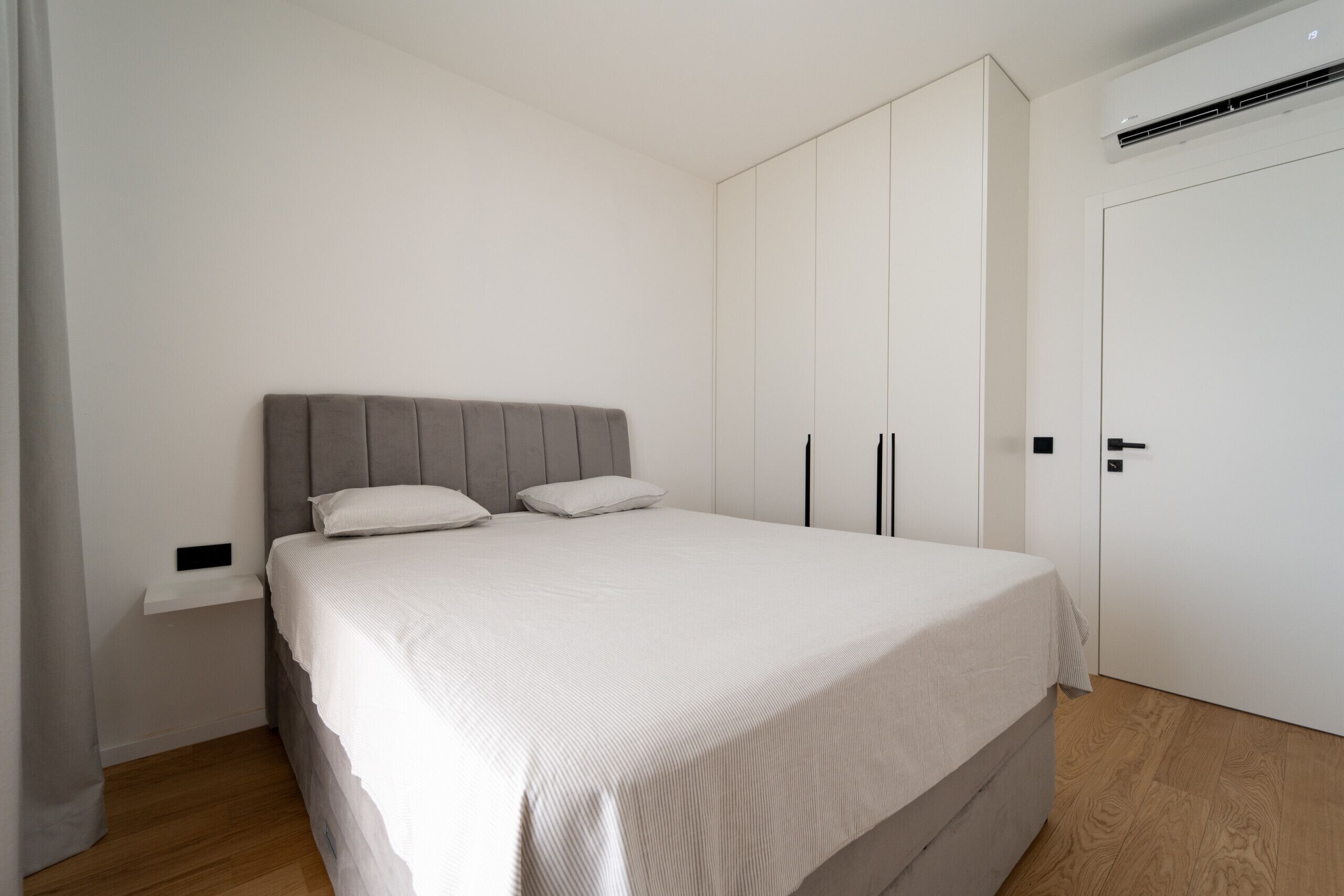 A bedroom with a bed, a wardrobe, and a bedside table.
