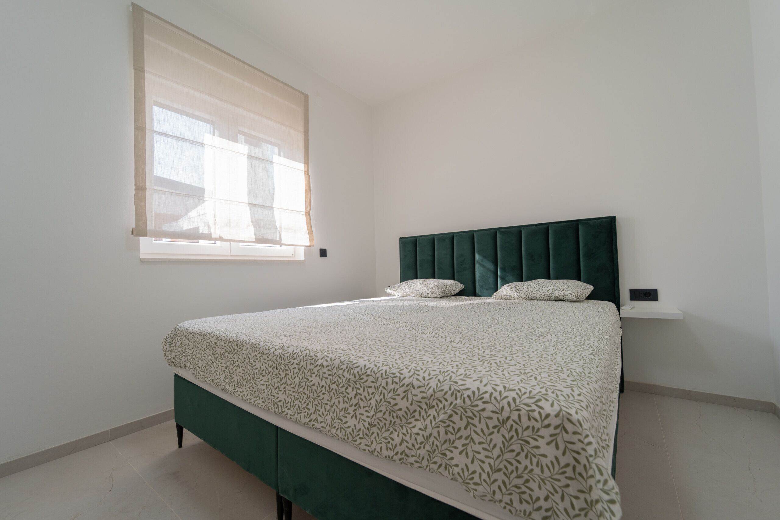 Una camera da letto con un letto, una finestra con persiane e un comodino.