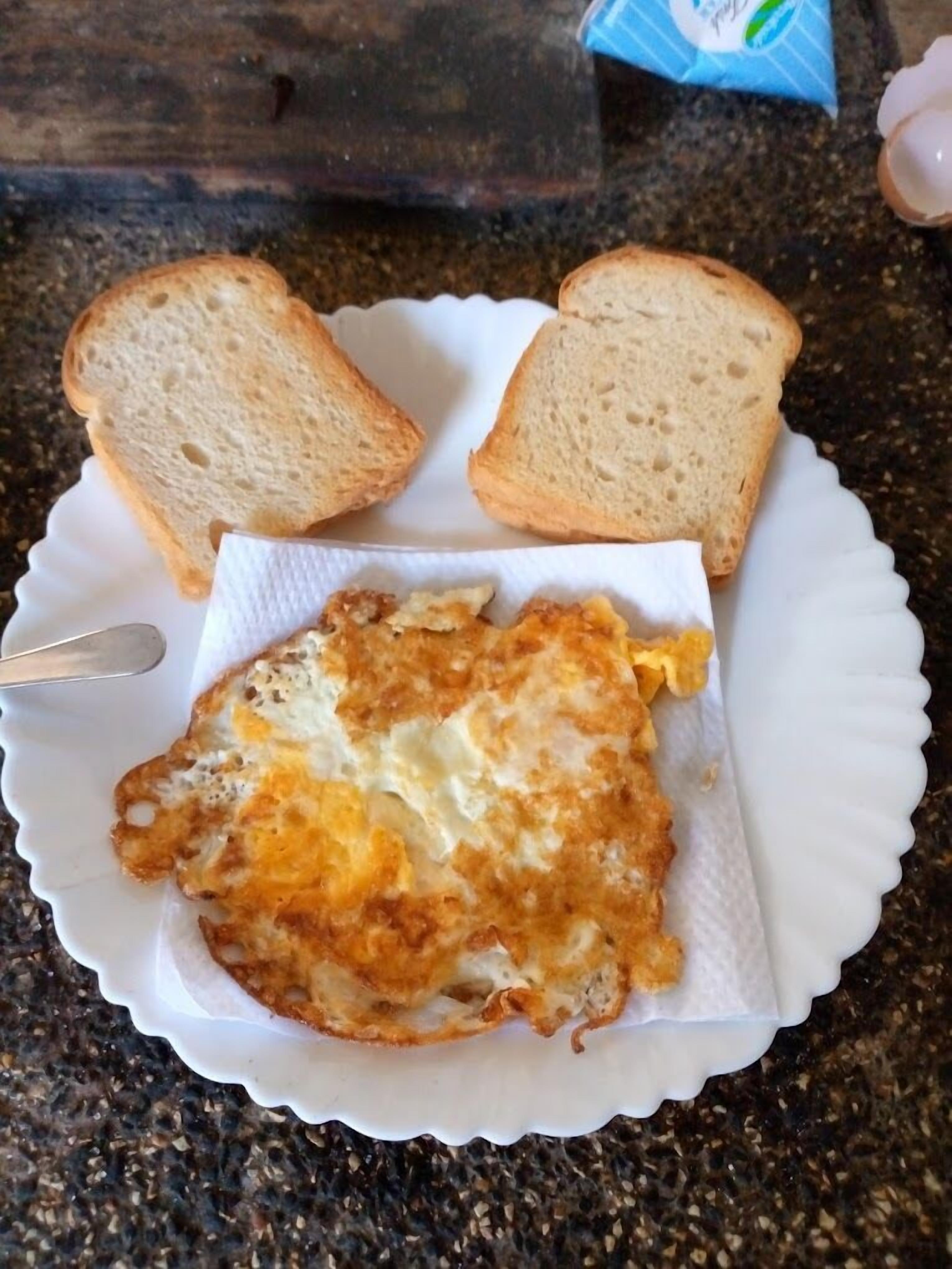 A plate with a fried egg and two slices of bread on a granite countertop.