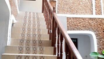 A staircase with patterned tiles and wooden railings leading to a building with white walls and stone accents.