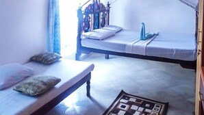 Um quarto com uma cama, um banco e um tapete estampado.