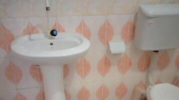 Une salle de bain avec un lavabo sur colonne blanc, des toilettes et des carreaux de sol à motifs.