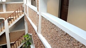 Interior com vários níveis, escadas brancas, paredes claras, porta de madeira e um pequeno jardim.