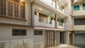 Un immeuble à plusieurs étages doté d’un balcon au deuxième étage, de grandes fenêtres et d’un garage avec des volets fermés.